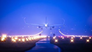 Ein Flugzeug im Landeanflug auf einen Flughafen bei Nacht.