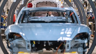 Ein Mitarbeiter der Porsche AG montiert in einer Produktionshalle des Porsche-Stammwerks einen Porsche Taycan. Tausende Stellen in der deutschen Autoindustrie wurden 2024 abgebaut. Welche Herausforderungen müssen Hersteller angehen, um aus der Krise zu kommen?