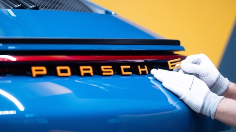Ein Mitarbeiter der Porsche AG bringt in der Porsche Sonderwunsch-Manufaktur einen Schriftzug an einem Porsche 911 ST an. Bilanz 2024: Ist der Sportwagenhersteller zu abhängig von China?