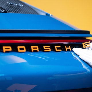 Ein Mitarbeiter der Porsche AG bringt in der Porsche Sonderwunsch-Manufaktur einen Schriftzug an einem Porsche 911 ST an. Bilanz 2024: Ist der Sportwagenhersteller zu abhängig von China?