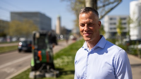 Frank Uekermann, Amtsleiter des Garten- und Tiefbauamts der Stadt Freiburg, steht neben einem noch zu mähenden Grünstreifen. 