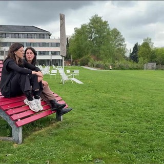 zwei junge Psychotherapeutinnen auf einer Bank im Park