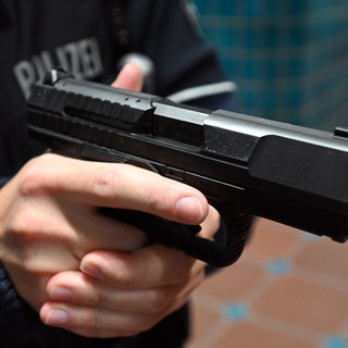 Ein Polizist hält eine Pistole vom Typ Walther P99 in den Händen.