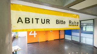 Ein Schild mit der Aufschrift "Abitur - bitte Ruhe!" hängt im Eingangsbereich einer Schule. 