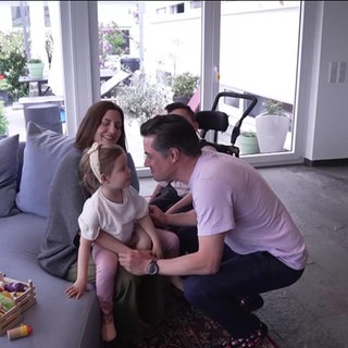 Eine vierköpfige Familie sitzt auf der Couch.