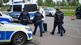 Polizeibeamte weisen einen Mann zurück und begleiten ihn zur französischen Grenze. 