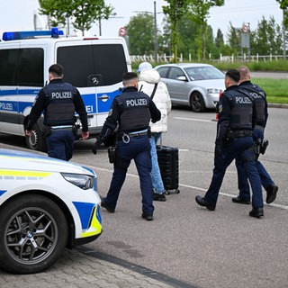 Polizeibeamte weisen einen Mann zurück und begleiten ihn zur französischen Grenze. 