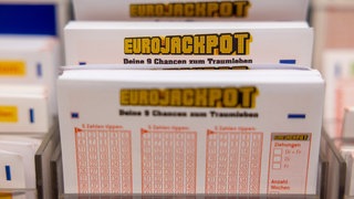 Eurojackpot Spielscheine stehen in einem Regal in einer Lotto-Annahmestelle.