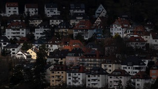 Vereinzelte Gebäude werden in der Stuttgarter Innenstadt durch ein Wolkenloch von der Sonne angestrahlt.
