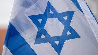Die israelische Flagge weht bei einer Demonstration.
