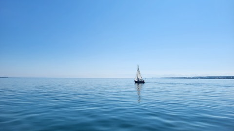 Ein Segelboot fährt auf dem Bodensee zwischen Konstanz und Meersburg.