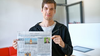 Julien Ferrat hält das aktuelle Amtsblatt mit seinem Artikel in den Händen.