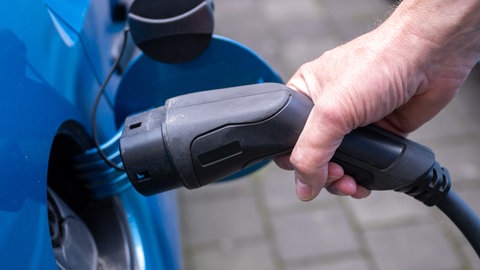Ein Ladekabel wird in ein E-Auto gesteckt.