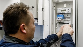 Ein Elektriker installiert einen Smartmeter, einen intelligenten Stromzähler, in einem Zählerschrank.