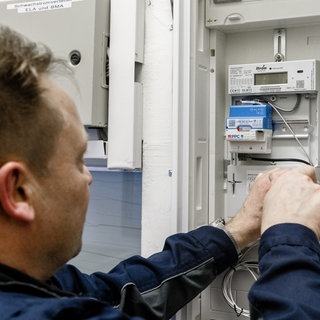 Ein Elektriker installiert einen Smartmeter, einen intelligenten Stromzähler, in einem Zählerschrank.