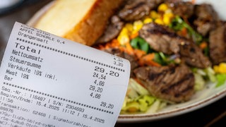 Eine Rechnung neben einem vollen Teller in einem Restaurant. (Symbolbild).