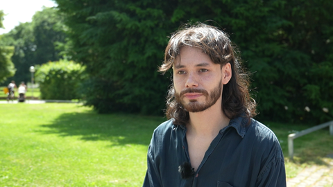 Jethro Escobar Ventura steht vor einem Gebüsch.