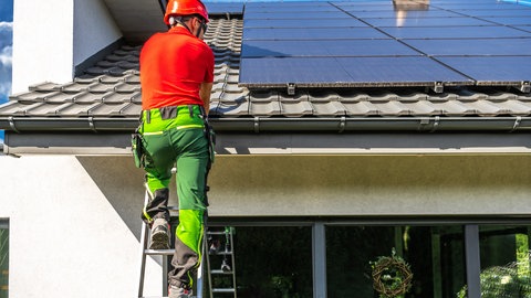 Installateur montiert Solarpanele auf einem privaten Hausdach