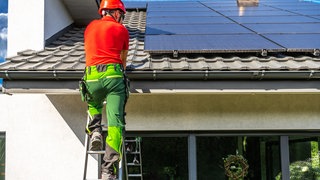 Installateur montiert Solarpanele auf einem privaten Hausdach