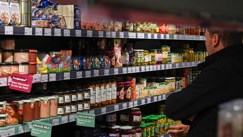 Ein Mann steht vor einem gefüllten Supermarkt-Regal. Mini-Supermärkte haben in Baden-Württemberg schon jetzt sonntags geöffnet - die BW-Grünen wollen dafür eine rechtsgrundlage schaffen.