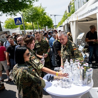Veteranninen und Veteranen verteilen Wasser.