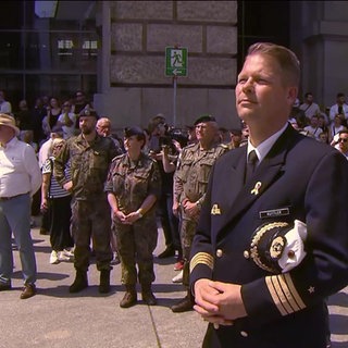Ein Veteran steht in Uniform vor einer Menschenmenge