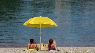 Eine Paar sonnt sich am Badesee. Der deutsche Wetterdienst warnt vor der Gefahr durch UV-Strahlungen in BW