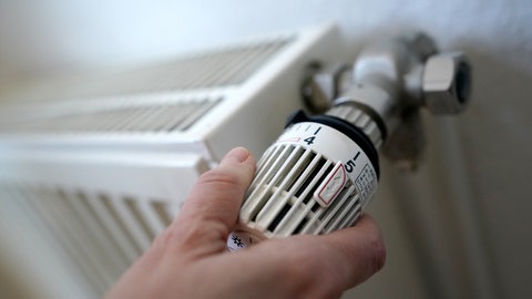 Eine Person dreht am Heizungsthermostat. Bis 2028 müdden alle Städte und Gemeiden im Land einen Wärmeplan vorlegen