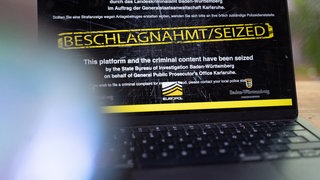 Ein Laptop, auf dem man eine beschlagnahmte Website sieht, steht auf einem Tisch.
