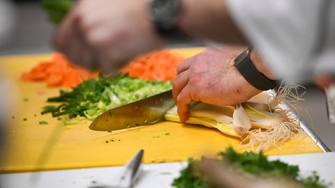 Ein Koch schneidet Gemüse.