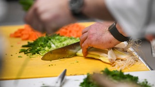 Ein Koch schneidet Gemüse.