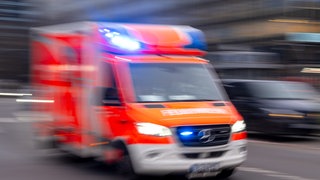 Ein Rettungswagen der Feuerwehr fährt mit Blaulicht zum Einsatz