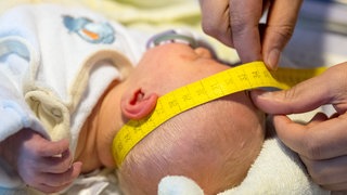 Eine Hebamme kümmert sich um einen Säugling.