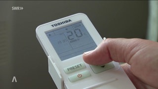Eine Person hält ein Gerät in der Hand, auf dem eine Temperatur angezeigt wird