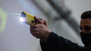 Ein Polizeibeamter demonstriert einen Schuss mit einem Taser.