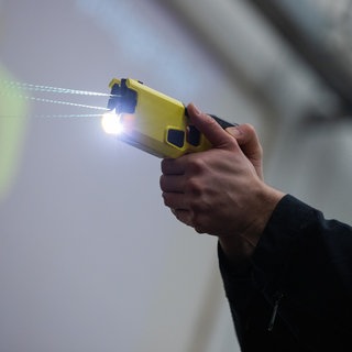 Ein Polizeibeamter demonstriert einen Schuss mit einem Taser.