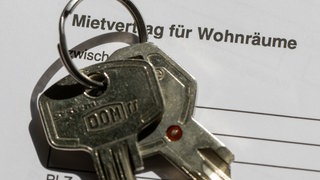 Ein Wohnungsschlüssel liegt auf einem Mietvertrag für eine Wohnung.