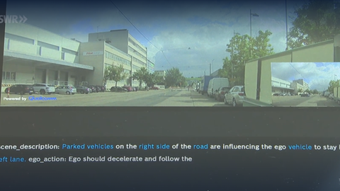 Ein Monitor im Auto zeigt die Szene der Umgebung, darunter stehen auf englisch kurze Beschreibungen des Umfelds
