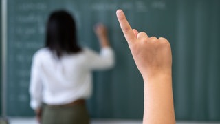  Ein Schüler meldet sich per Handzeichen in einem Klassenraum. Viele junge Lehrkräfte sind in Baden-Württemberg ohne Job.