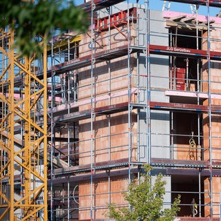 Ein Gerüst steht an der Baustelle eines Neubaus. 