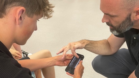 Medientrainer Clemens Beisel zeigt einem Schüler der neunten Klassen der Gemeinschaftsschule Illingen-Maulbronn (Enzkreis) Dinge auf einem Smartphone. 