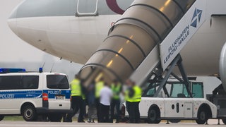 Abschiebung nach Afghanistan: Menschen besteigen ein Flugzeug, vor dem Fahrzeuge der Bundespolizei stehen