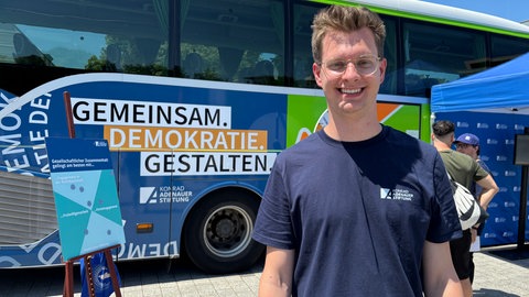 Ein junger Mann mit Brille lächelt in die Kamera: Konstantin Gerbrich vom Demokratiebus will den Menschen vor allem zuhören