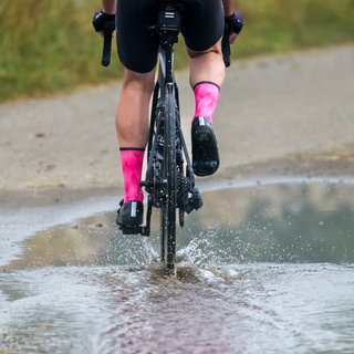 Neue Woche bringt Regen: Ein Mann fährt mit seinem Rennrad durch eine Pfütze. (Archiv)