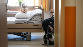 Ein Bewohner sitzt in einem Pflegeheim in seinem Zimmer in einem Rollstuhl.