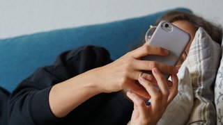 Eine Person hält ein Smartphone in der Hand - KI-Chatbots am Handy werden bei Mental-Health-Problemen zunehmend beliebter (Symbolbild)