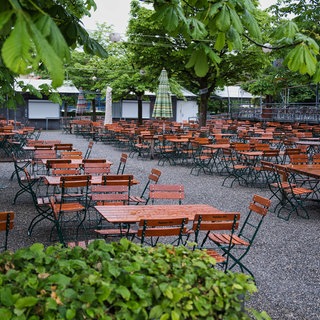 Leere, nasse Biertische in einem Biergarten: Das Regenwetter wirkt sich auf die Außengastronomie aus.