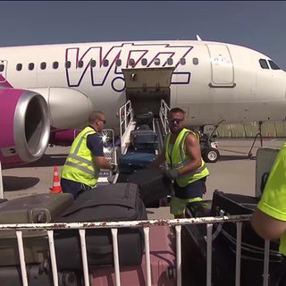 Rollfeldarbeiter holen Gepäck aus einem Flugzeug