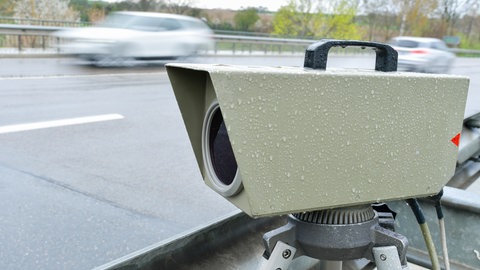 Ein Auto fährt an einem Messgerät zur Geschwindigkeitskontrolle von Fahrzeugen vorbei. 