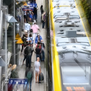 Zugreisende stehen am Bahnhof Überlingen (Bodenseekreis), um in den Zug einzusteigen.